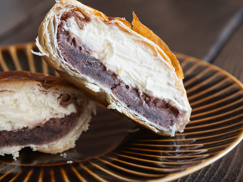 A puff pastry sweet filled with red bean paste and fresh cream. cross section.