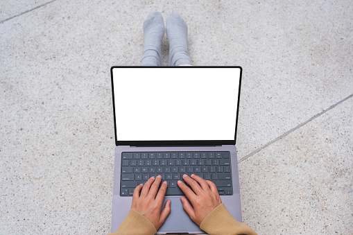 Top view mockup image of a woman working and typing on laptop computer with blank screen