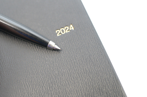 A ballpoint pen placed on a diary with a black cover
