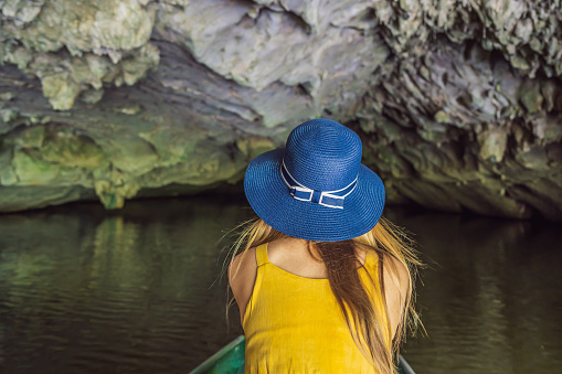 Woman tourist in boat on the lake Tam Coc, Ninh Binh, Viet nam. It's is UNESCO World Heritage Site, renowned for its boat cave tours. It's Halong Bay on land of Vietnam. Vietnam reopens borders after quarantine Coronovirus COVID 19.