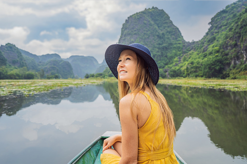 Woman tourist in boat on the lake Tam Coc, Ninh Binh, Viet nam. It's is UNESCO World Heritage Site, renowned for its boat cave tours. It's Halong Bay on land of Vietnam. Vietnam reopens borders after quarantine Coronovirus COVID 19.