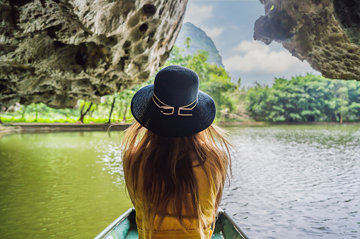 Woman tourist in boat on the lake Tam Coc, Ninh Binh, Viet nam. It's is UNESCO World Heritage Site, renowned for its boat cave tours. It's Halong Bay on land of Vietnam. Vietnam reopens borders after quarantine Coronovirus COVID 19.