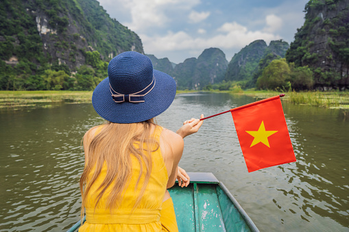 Woman tourist in boat on the lake Tam Coc, Ninh Binh, Viet nam. It's is UNESCO World Heritage Site, renowned for its boat cave tours. It's Halong Bay on land of Vietnam. Vietnam reopens borders after quarantine Coronovirus COVID 19.