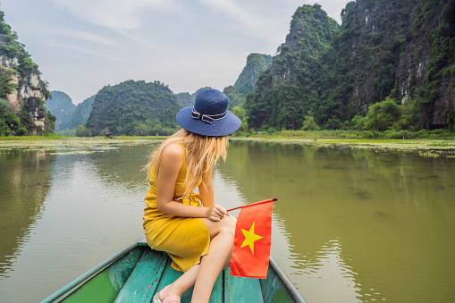 Woman tourist in boat on the lake Tam Coc, Ninh Binh, Viet nam. It's is UNESCO World Heritage Site, renowned for its boat cave tours. It's Halong Bay on land of Vietnam. Vietnam reopens borders after quarantine Coronovirus COVID 19
