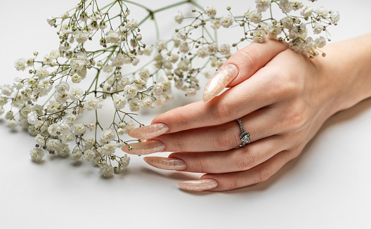 Manicured nails with pearlescent nail polish.  The nails are covered with pearl gel polish on white background
