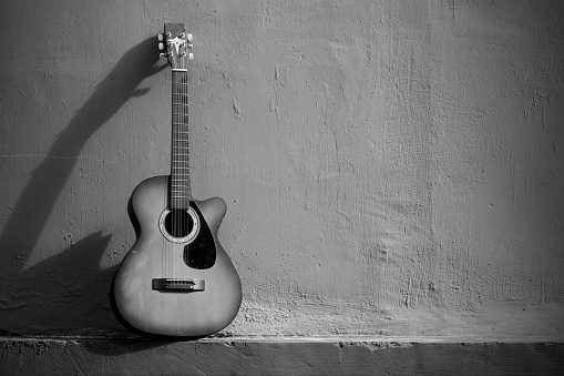 Black and white wallpaper with an old guitar ornament on a plain wall. Suitable as a background image for various design needs, quotes, posters, etc.