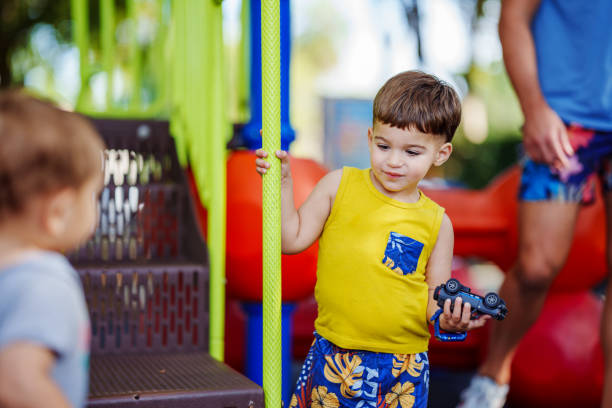 An adorable toddler boy of Puerto Rican descent plays with his friends and father on the playground of a public park in a Florida neighborhood.