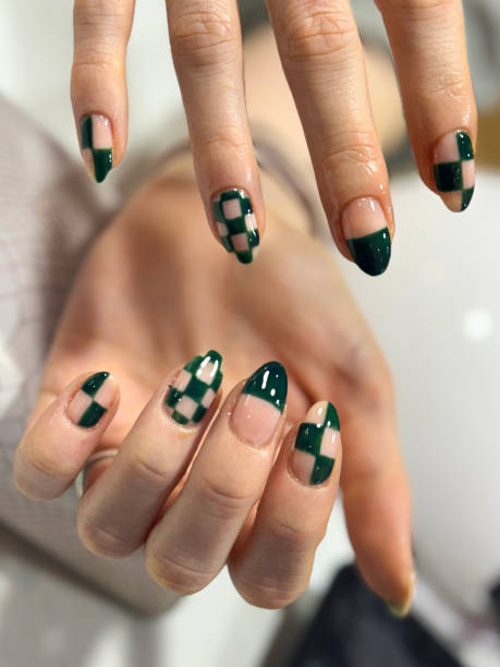 Close-up image of unrecognisable woman's hands displaying nail art, clawed fingers showing green checked pattern nail varnish manicure design, nail salon, elevated view