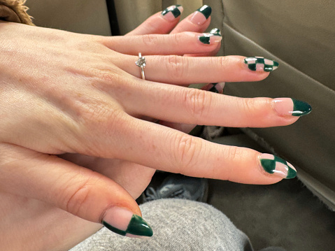 Stock photo showing close-up view of a woman displaying her engagement ring and manicured painted nails design.