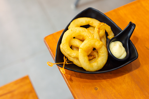 Onion rings with dipping sauce on a triangular shaped plate Place the edge of the wooden table menu in restaurant