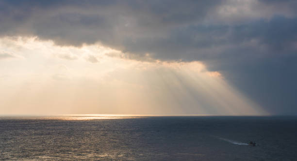 istock Majestic ocean sunrise scenery with sunlight shining through dark clouds 1994344240
