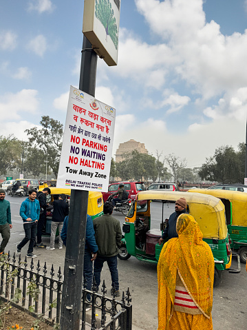 New Delhi, India - January 6, 2024: Stock photo showing close-up view of 'No Parking, No Waiting, No Halting' sign on street corner where auto rickshaw drivers are parked to collect passengers.