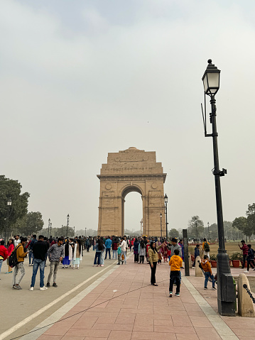 India Gate, New Delhi, India - January 6, 2024: Stock photo showing close-up view of crowds of tourists walking down the Kartavya Path (Rajpath) viewing the India Gate, originally called the All India War Memorial in New Delhi, India.