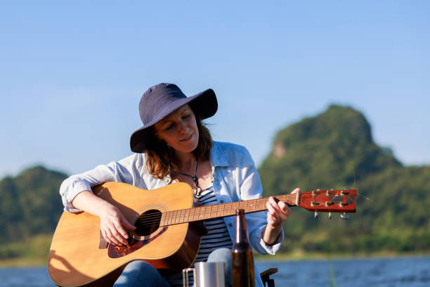 istock female caucasian playing guitar by the lake, 1994359725