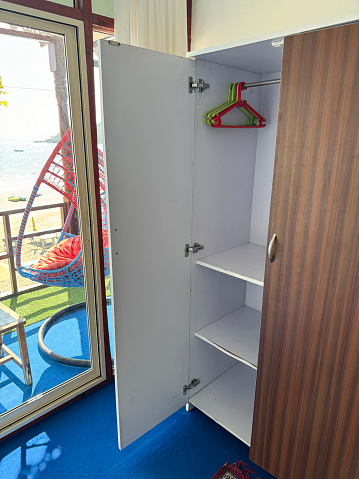 Stock photo showing an empty hotel closet with plastic coat hangers on a metal rail.