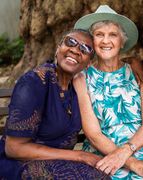 istock Senior women smiling while sitting together on a park bench 1994419783