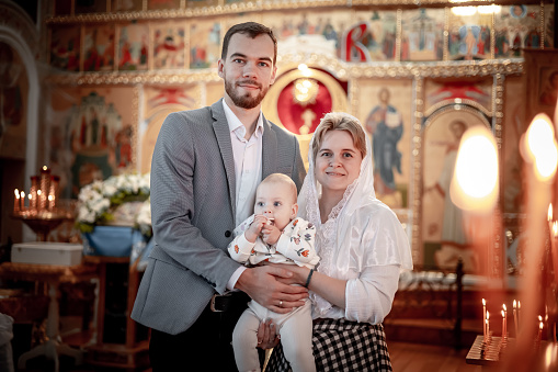 a family with children in an Orthodox Christian church or temple are praying or have come to the sacrament of baptism, believers in a holy place, introducing children to the faith.