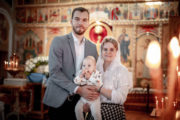 a family with children in an Orthodox Christian church or temple are praying or have come to the sacrament of baptism, believers in a holy place, introducing children to the faith a family with children in an Orthodox Christian church or temple are praying or have come to the sacrament of baptism, believers in a holy place, introducing children to the faith. pics of the godmother stock pictures, royalty-free photos & images
