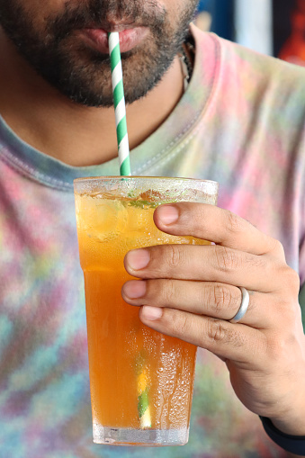 Stock photo showing close-up view of citrus orange mock cocktail with ice cubes and lime slice in drinking glass covered in condensation.