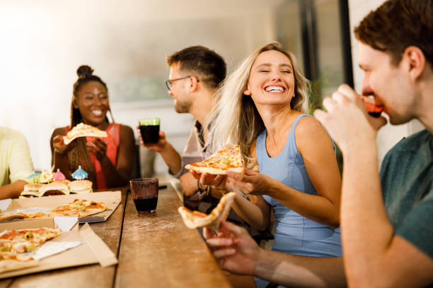Cheerful woman eating pizza with her friends on a patio.