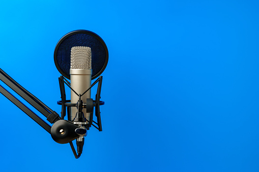 Professional microphone stand over blue studio background close up