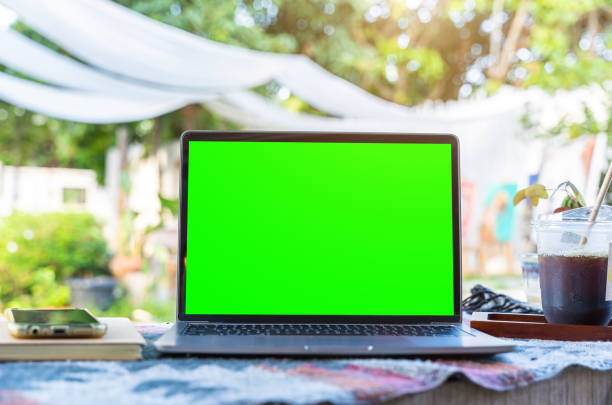 istock Mockup of laptop computer with empty screen with coffee cup and smartphone on table beside the window of the coffee shop background,White screen 1994440842
