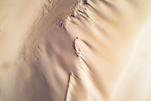 Strong wind shaping dry arid desert landscape scene with uniquely shaped golden sand dunes in Western Australia