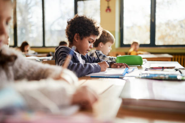 istock Black schoolboy and his friends on a class at elementary school. 1994447652