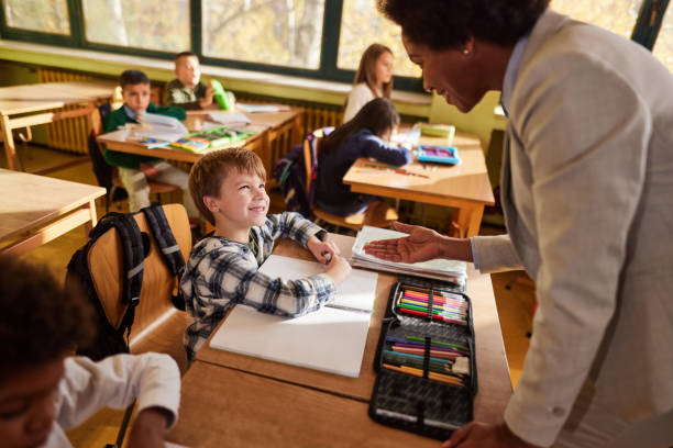 istock Happy black professor assisting schoolboy on a class at school. 1994450293
