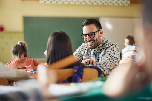 Portrait of diligent schoolkids and their teacher talking at lesson