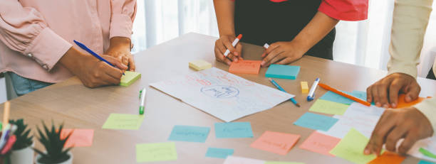 istock Young business group brainstorms ideas on colorful sticky notes. Variegated. 1994459138
