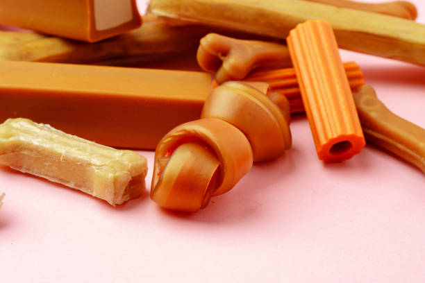Dog chew bone and sticks on pink background close up