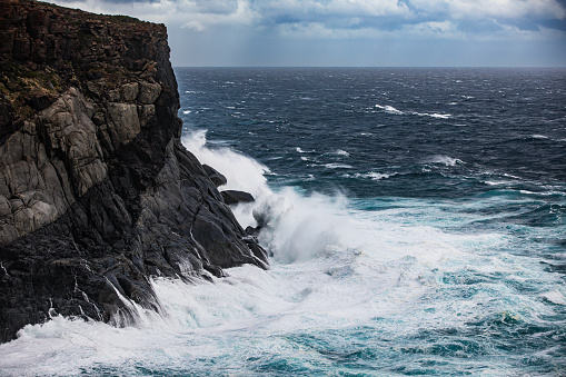 Rough dangerous ocean waves surging on cliff face during storm. Photographed off the south west coast of Western Australia.