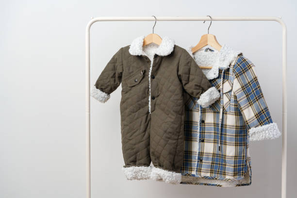 istock Two kids winter coats hanging on hangers against white wall 1994466234