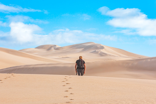 Young male backpacker walking into dry arid desert landscape in Western Australia