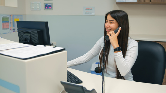 Receptionist smiling while talking on a landline phone