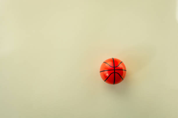 Small basketball ball against colored background.