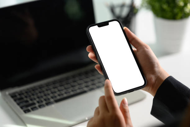 istock Unrecognizable businesswoman using smartphone at office desk0 Empty screen for your text message 1994572216