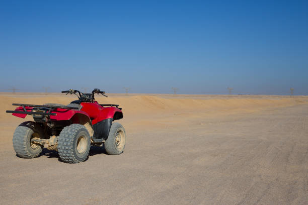 Red quad bike in the Arabian desert standing on safari road. Concept of active extreme sports in the sandy desert on sunny day
