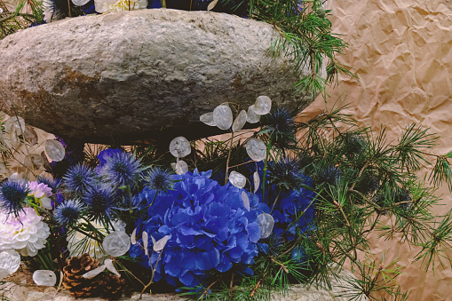 Floral arrangement of blue flowers and stone.