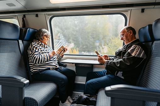 Beautiful senior couple using their phones while riding in a train in Switzerland.