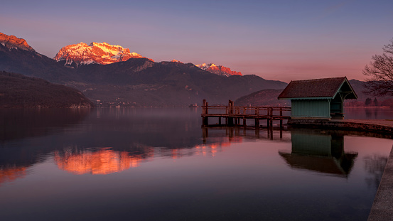 Landscape of Lake Annecy surrounded by mountains at sunset in winter around Saint-Jorioz