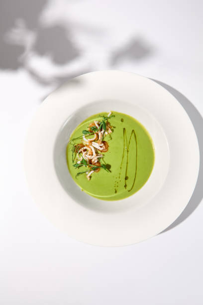 istock Top view of spinach cream soup with squid garnished with herbs, casting a soft shadow on white, ideal for modern cuisine publications 1994644418