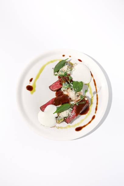 istock Pan-seared veal cutlet with cheese espuma and Demi-glace sauce, artfully arranged on a white plate, top view - ideal for modern gastronomy concepts 1994644737