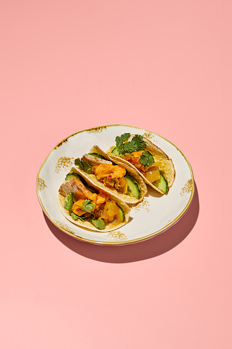 Gluten-free tacos with sweet potato mousse and turkey on a vintage plate with pink background.