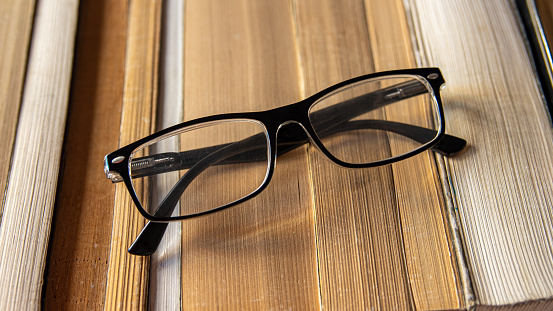 glasses with glass for optical vision with background of reading book spines