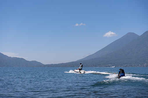 A young Hispanic man practices jet-skiing on a lake, showcasing dynamic water sports action