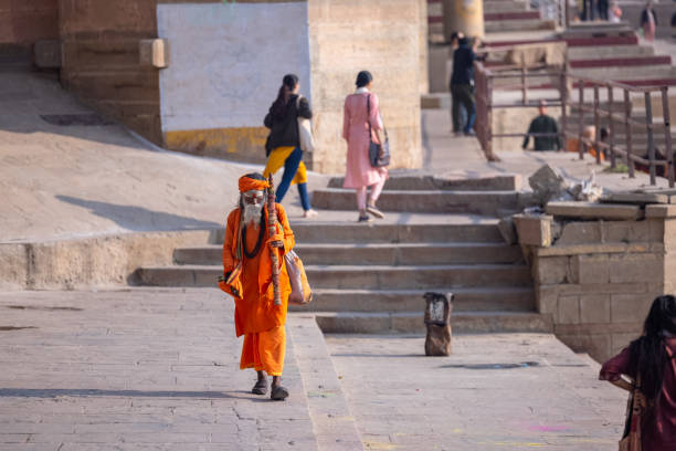Varanasi, Uttar Pradesh, India - March 2023: Portrait of Unidentified Indian sadhu baba in traditional clothes walking on ghats near river ganges in varanasi city.