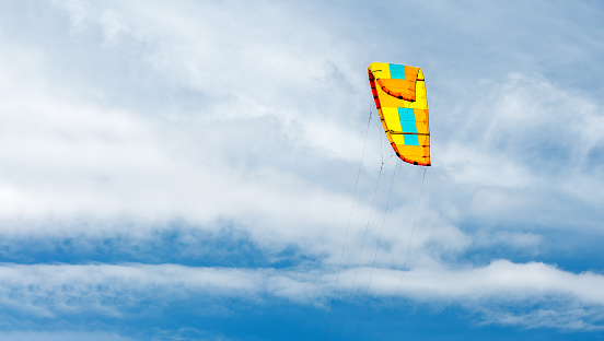 Colorful paraglider against the blue sky. Paraglider sail preparing to fly. Sky background and flying kite. Extreme sports.