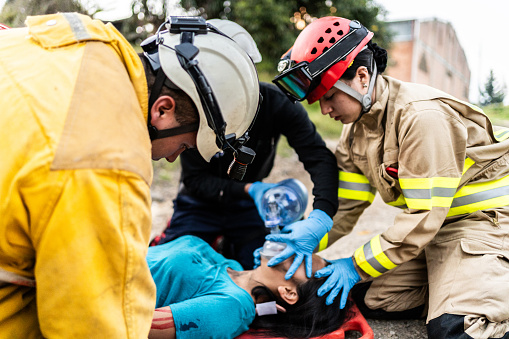 Paramedics using manual oxygen pump on an accident victim